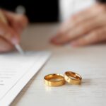 Zwei goldene Ringe neben einem Ehevertrag