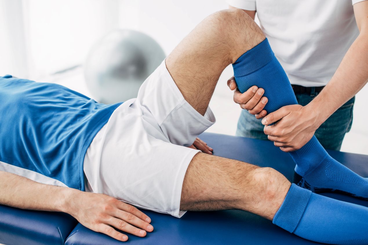 Sportmediziner Köln untersucht Knie eines Sportlers auf Behandlungsliege